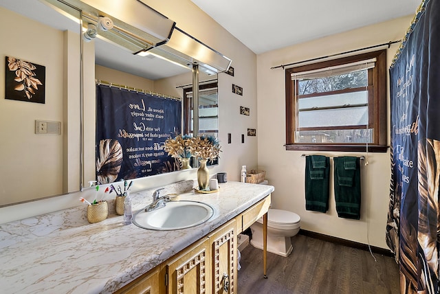 full bathroom featuring baseboards, wood finished floors, toilet, and vanity
