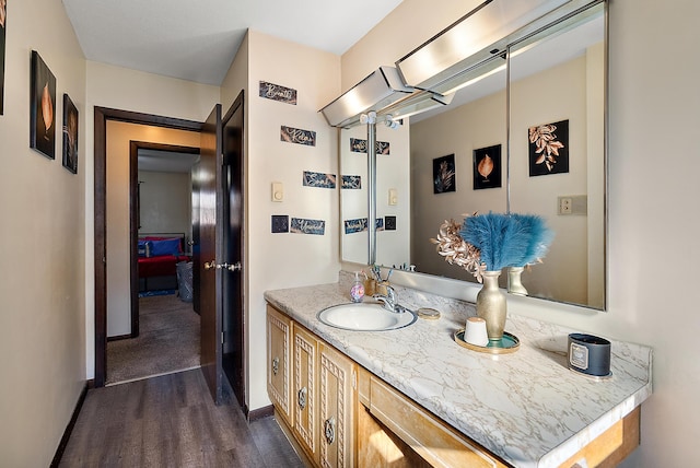 bathroom with baseboards, wood finished floors, and vanity