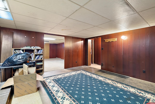 finished basement featuring wood walls and a drop ceiling