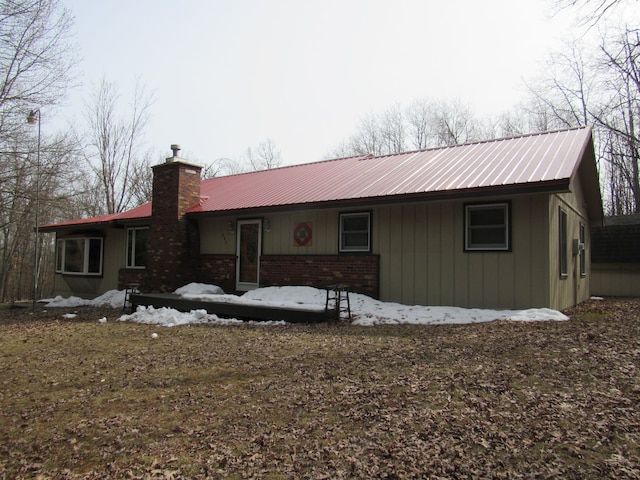 view of front of house featuring brick siding, a chimney, and metal roof
