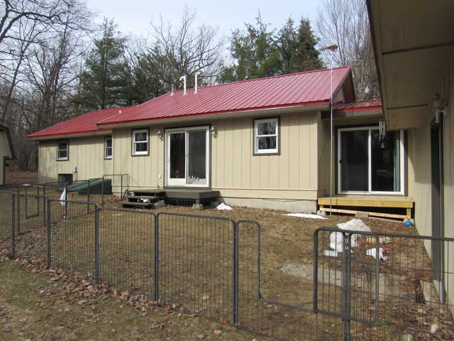 rear view of house with fence private yard, metal roof, and entry steps