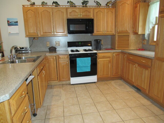 kitchen with light countertops, range with gas cooktop, a sink, black microwave, and light tile patterned floors
