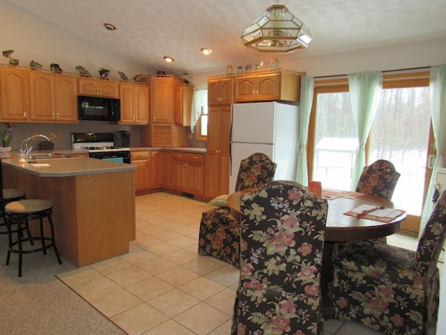 kitchen featuring a sink, freestanding refrigerator, black microwave, light tile patterned floors, and range with gas cooktop