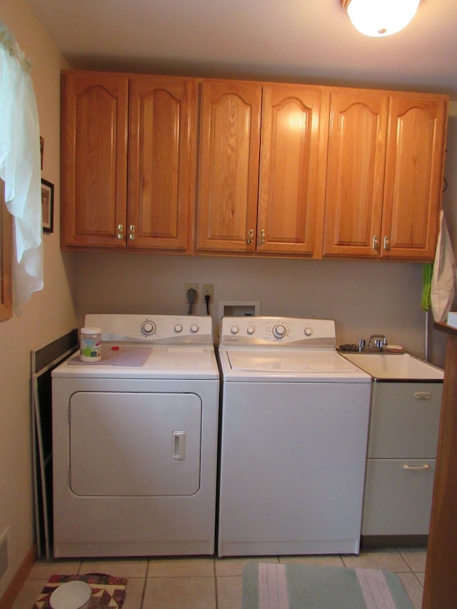 clothes washing area with light tile patterned flooring, cabinet space, and washing machine and dryer