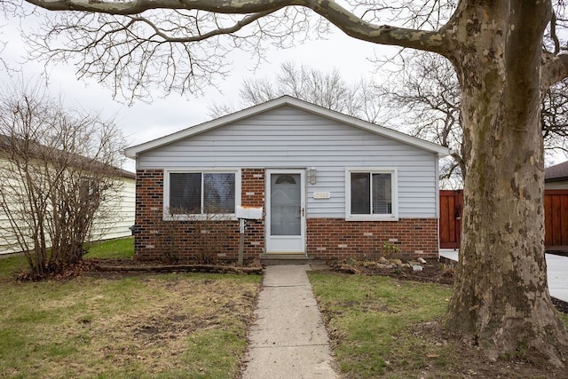 bungalow featuring a front yard, fence, and brick siding
