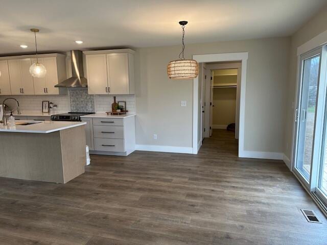 kitchen with wall chimney range hood, baseboards, a healthy amount of sunlight, and a sink