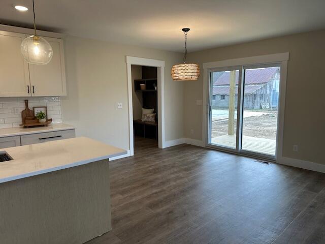 kitchen featuring backsplash, white cabinetry, baseboards, and light countertops
