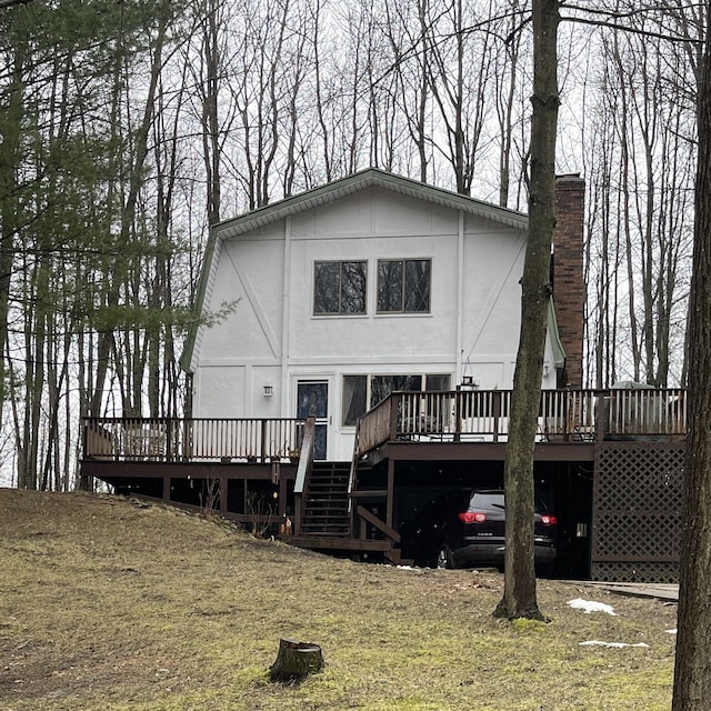 12181 Trail Creek Dr, Stanwood, MI 49346 - back of property with stucco siding, a chimney, a wooden deck, and a carport