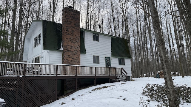 12181 Trail Creek Dr, Stanwood, MI 49346 - snow covered rear of property featuring cooling unit, a gambrel roof, roof with shingles, a deck, and a chimney