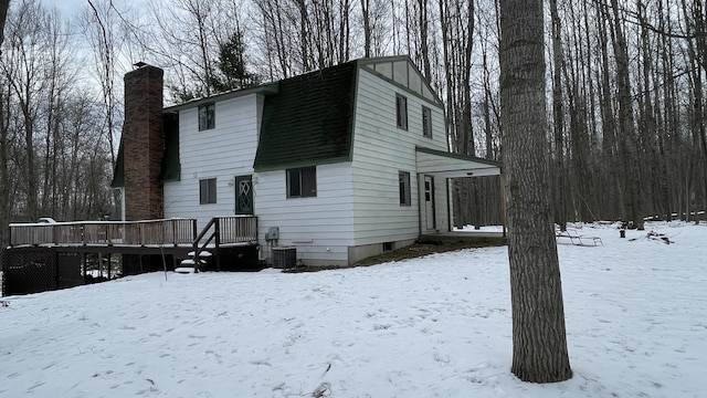 12181 Trail Creek Dr, Stanwood, MI 49346 - snow covered back of property with a gambrel roof, central AC unit, a deck, and a chimney