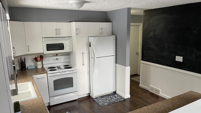 12181 Trail Creek Dr, Stanwood, MI 49346 - kitchen with a textured ceiling, visible vents, white appliances, dark wood-type flooring, and wainscoting