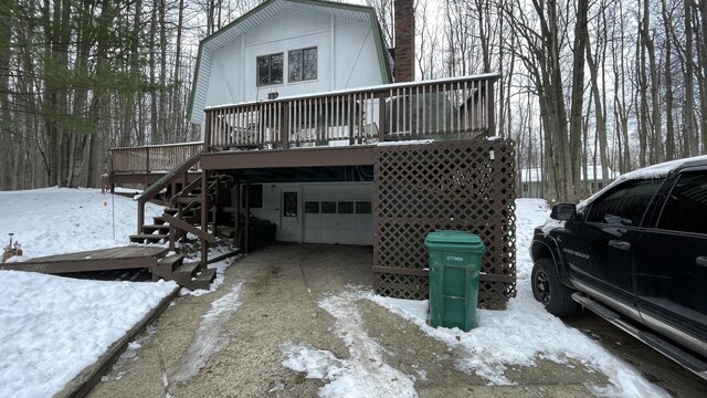 12181 Trail Creek Dr, Stanwood, MI 49346 - view of snowy exterior featuring a gambrel roof, driveway, stairway, a deck, and an attached garage