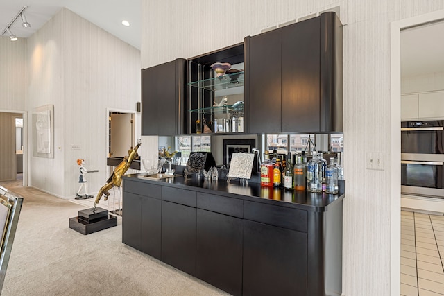bar featuring baseboards, wallpapered walls, light carpet, a sink, and double oven