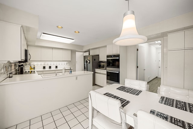 kitchen featuring a sink, light countertops, decorative backsplash, and appliances with stainless steel finishes