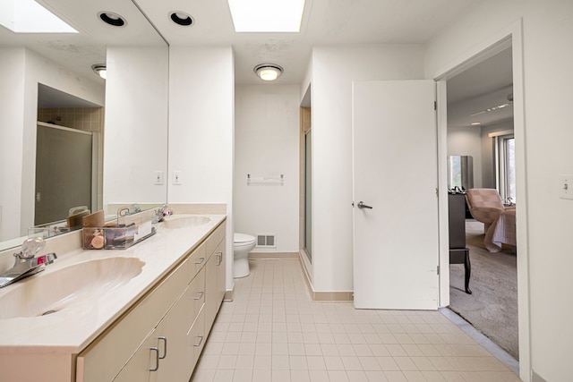 ensuite bathroom with visible vents, a sink, toilet, and a skylight