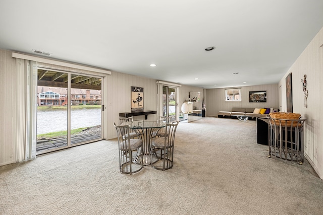 dining space featuring carpet floors, a water view, recessed lighting, and visible vents