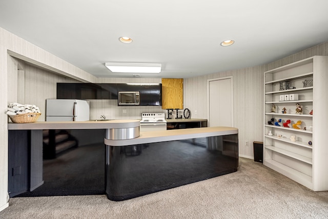 kitchen featuring stainless steel microwave, electric range oven, freestanding refrigerator, a kitchen breakfast bar, and light colored carpet