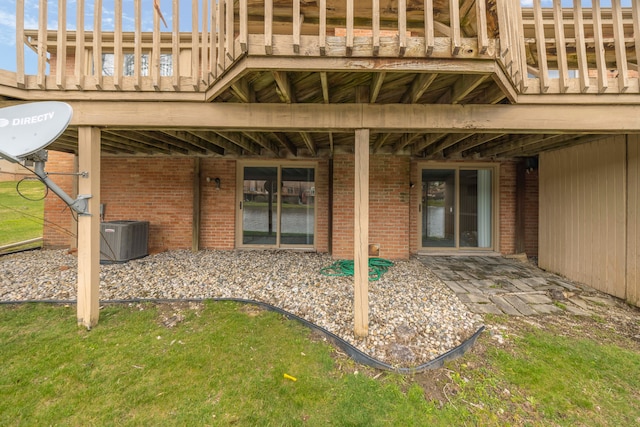 back of house featuring brick siding and central AC