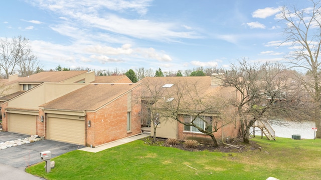 view of front of property with aphalt driveway, brick siding, a garage, and a front yard