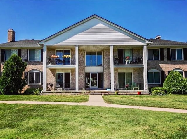 13940 Camelot Dr Unit 79, Sterling Heights, MI 48312 - view of front facade featuring a chimney, a balcony, a front lawn, and brick siding