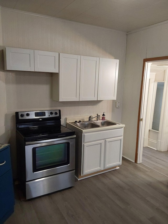 612 Lansing Ave, Jackson, MI 49202 - kitchen featuring electric range, white cabinets, wood finished floors, and ornamental molding