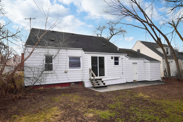 rear view of house featuring a shingled roof, entry steps, and a patio area