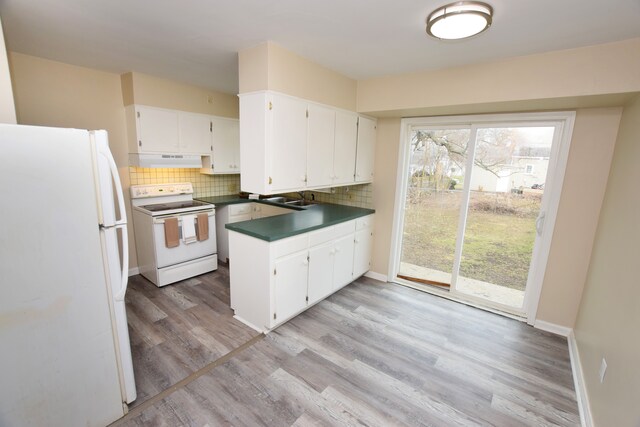 kitchen featuring white appliances, dark countertops, backsplash, and a peninsula