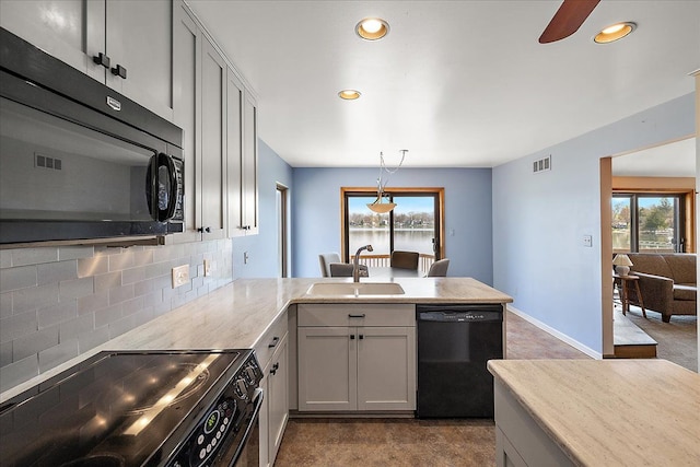 kitchen with a sink, visible vents, black appliances, a peninsula, and backsplash