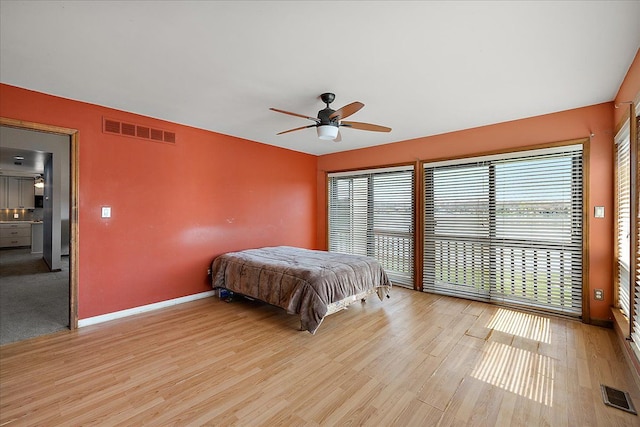 bedroom featuring visible vents, ceiling fan, light wood-style floors, and baseboards