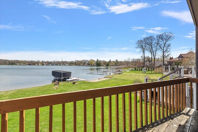 wooden terrace with boat lift, a dock, a water view, and a lawn