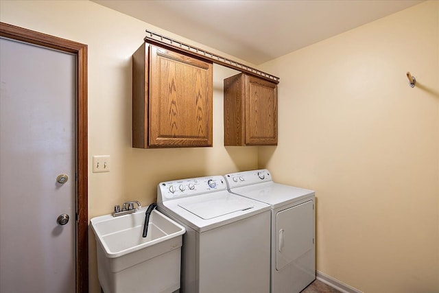 washroom with washing machine and clothes dryer, cabinet space, and a sink