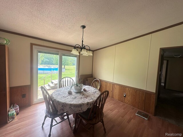 13027 Norman Rd, Brockway, MI 48097 - dining space featuring crown molding, a wainscoted wall, wood finished floors, a textured ceiling, and a chandelier