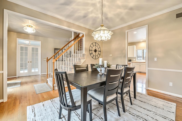 dining area featuring a notable chandelier, baseboards, stairway, and light wood finished floors