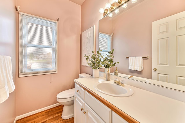 bathroom with baseboards, toilet, wood finished floors, and vanity
