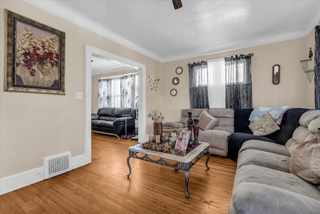 living area featuring plenty of natural light, visible vents, baseboards, and wood finished floors