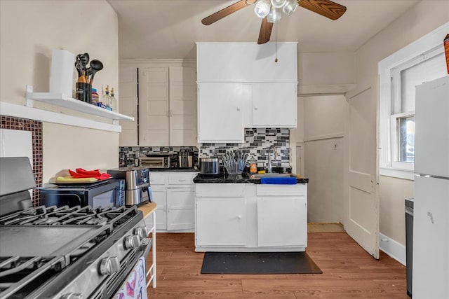 kitchen with white cabinets, a sink, ceiling fan, freestanding refrigerator, and gas stove