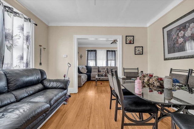 dining space featuring ceiling fan, light wood finished floors, and baseboards