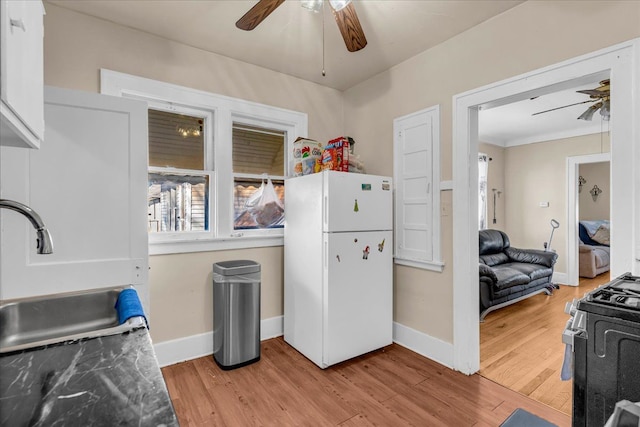 kitchen with light wood-style flooring, gas range, freestanding refrigerator, and ceiling fan