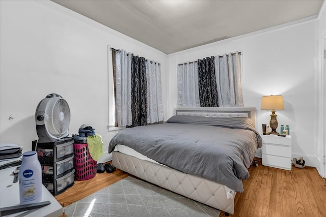 bedroom with baseboards, ornamental molding, and wood finished floors
