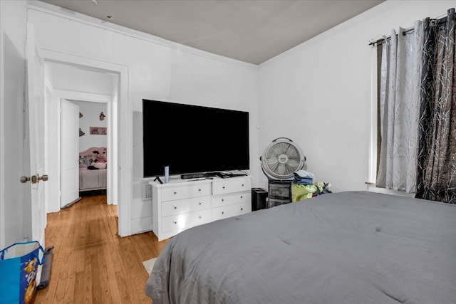 bedroom with ornamental molding and wood finished floors
