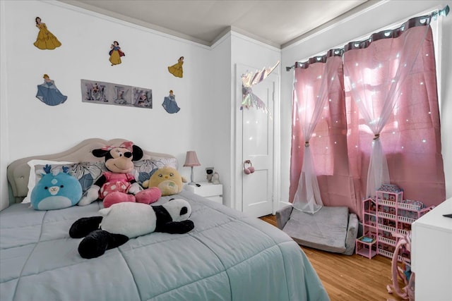 bedroom with ornamental molding and wood finished floors