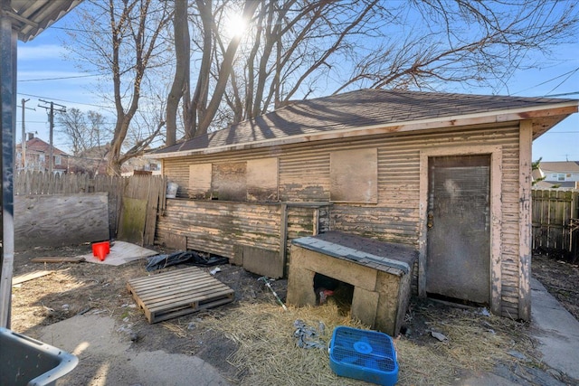 exterior space with an outbuilding, fence, and a shingled roof