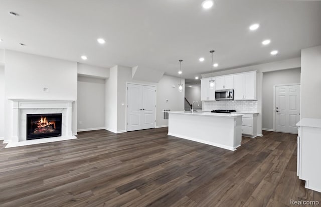 1466 Addison Cir, Walled Lake, MI 48390 - kitchen with stainless steel microwave, an island with sink, dark wood-style floors, open floor plan, and light countertops