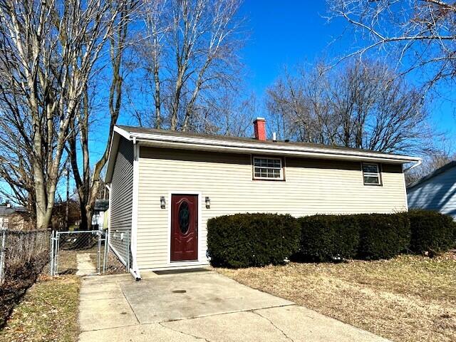 view of front of house with a chimney, a gate, and fence