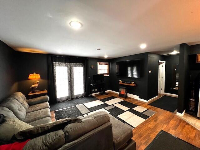 living area with baseboards, wood finished floors, and french doors