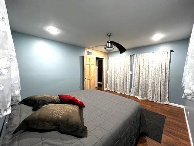 bedroom with baseboards, visible vents, a ceiling fan, and wood finished floors