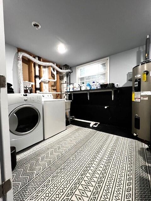 clothes washing area featuring water heater, washing machine and clothes dryer, and laundry area