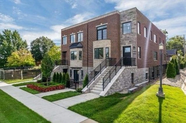 1219 N Main St, Rochester, MI 48307 - view of front facade featuring stone siding, a front yard, stairway, and fence