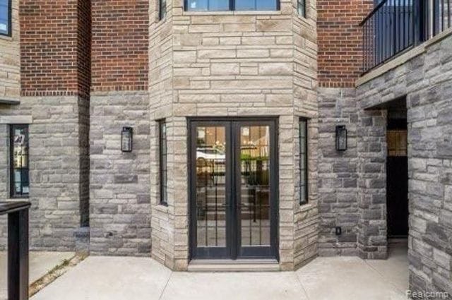 1219 N Main St, Rochester, MI 48307 - view of exterior entry with french doors, stone siding, and a patio