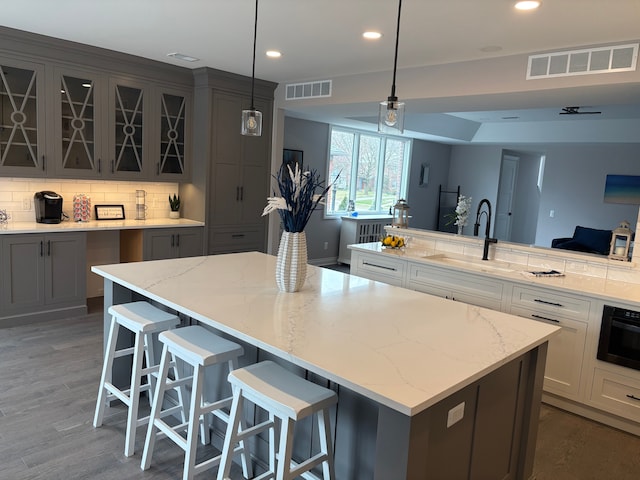1219 N Main St, Rochester, MI 48307 - kitchen featuring a sink, visible vents, a spacious island, and backsplash